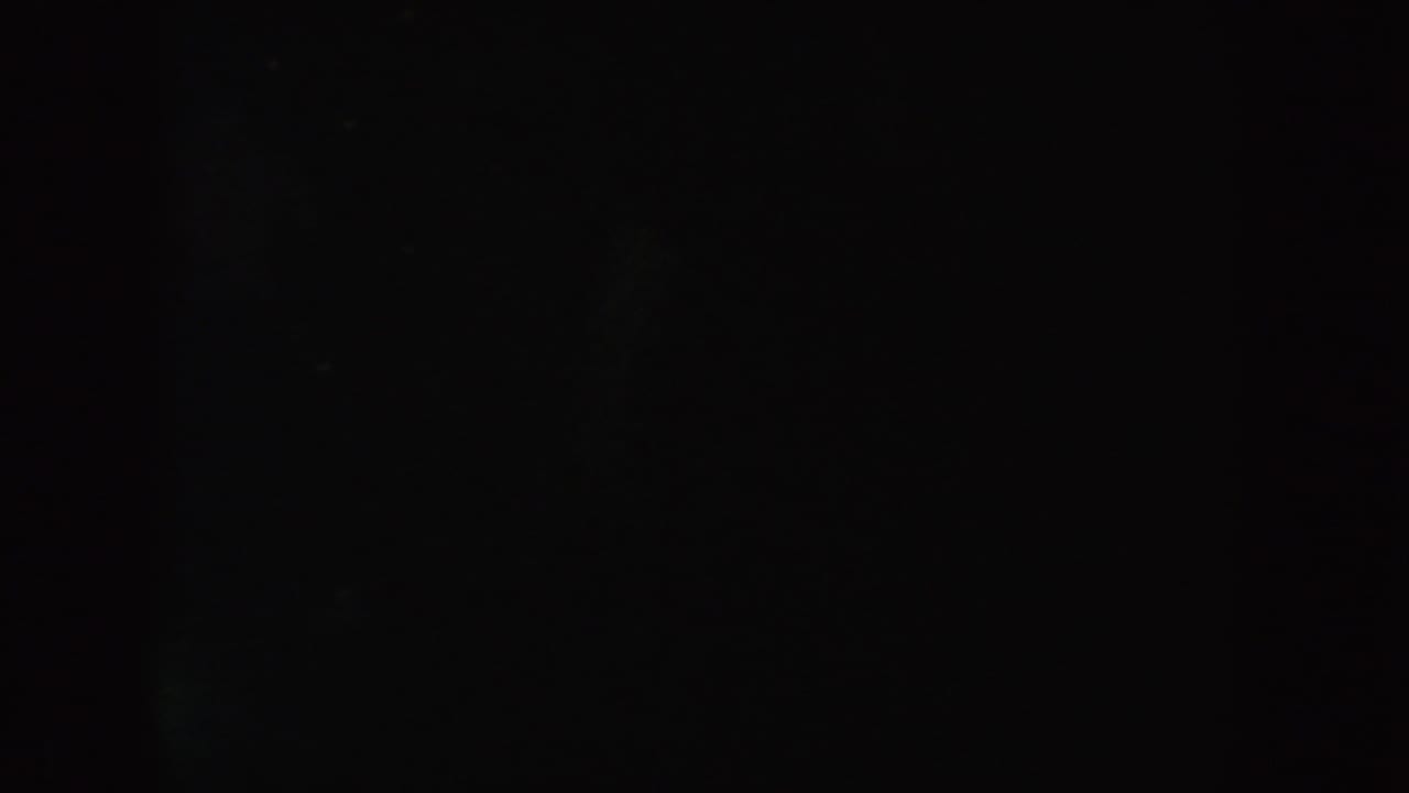 Underexposed 8mm frame from the 1954 South Dakota clip with soft greenish tones, darkness, and scattered film grain.