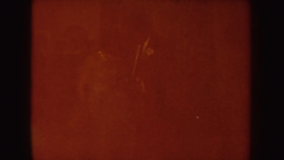 Orange-red 8mm transition frame with visible film scratches, grain, and dark border, likely from exposure or a cut.