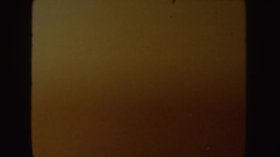 Dark yellow-brown 8mm transition frame with visible grain, soft exposure variation, and a black film edge.