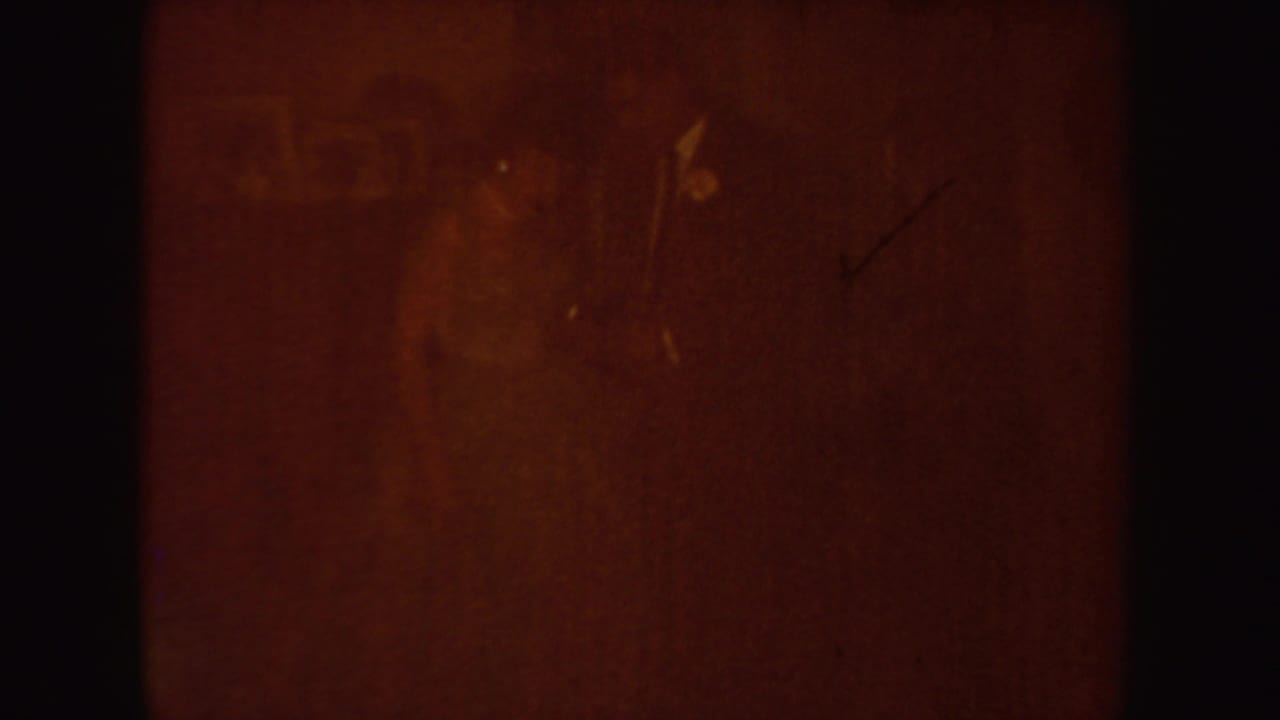 Amber light-leak frame with indistinct interior forms and film texture.