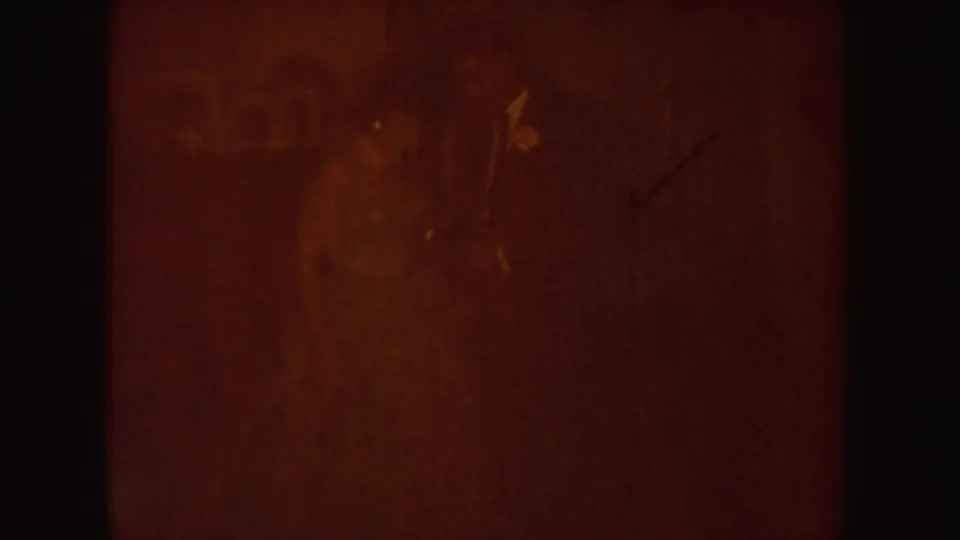 Amber-tinted 8mm frame dominated by light leak and grain, with only vague interior forms visible.