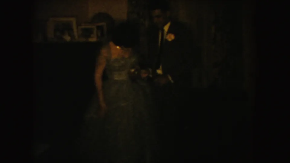 Very dark 1954 South Dakota 8mm frame showing a bride and groom standing together in an interior room.