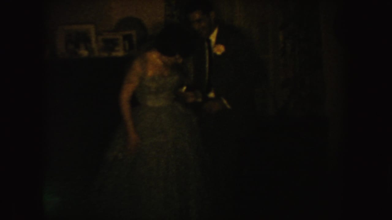 Bride and groom remain in a very dark indoor frame.