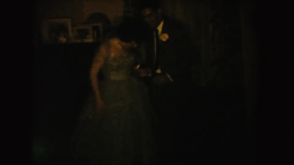 Low-light 8mm view of the wedding couple standing close together in a South Dakota interior, with details partly obscured.