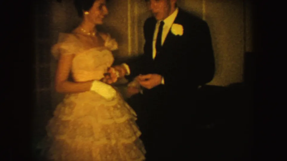 Warm 8mm frame of a South Dakota wedding couple facing each other, with the bride's gown and groom's boutonniere visible.