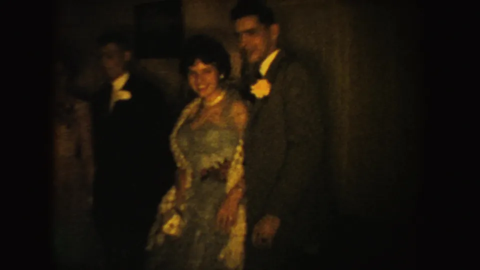A woman in a blue dress with floral trim stands near men in suits during a 1954 South Dakota formal gathering.