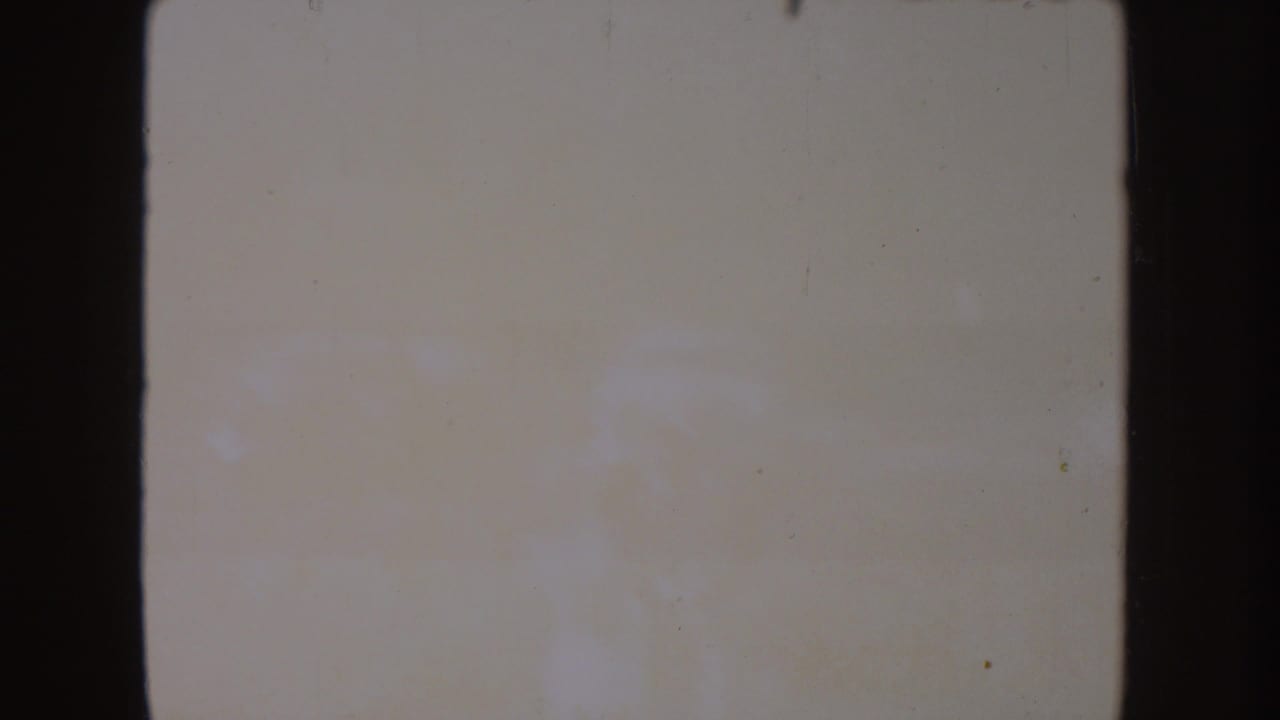 Nearly washed-out 8mm frame from the South Dakota lake clip, with faint shore shapes and visible film deterioration.