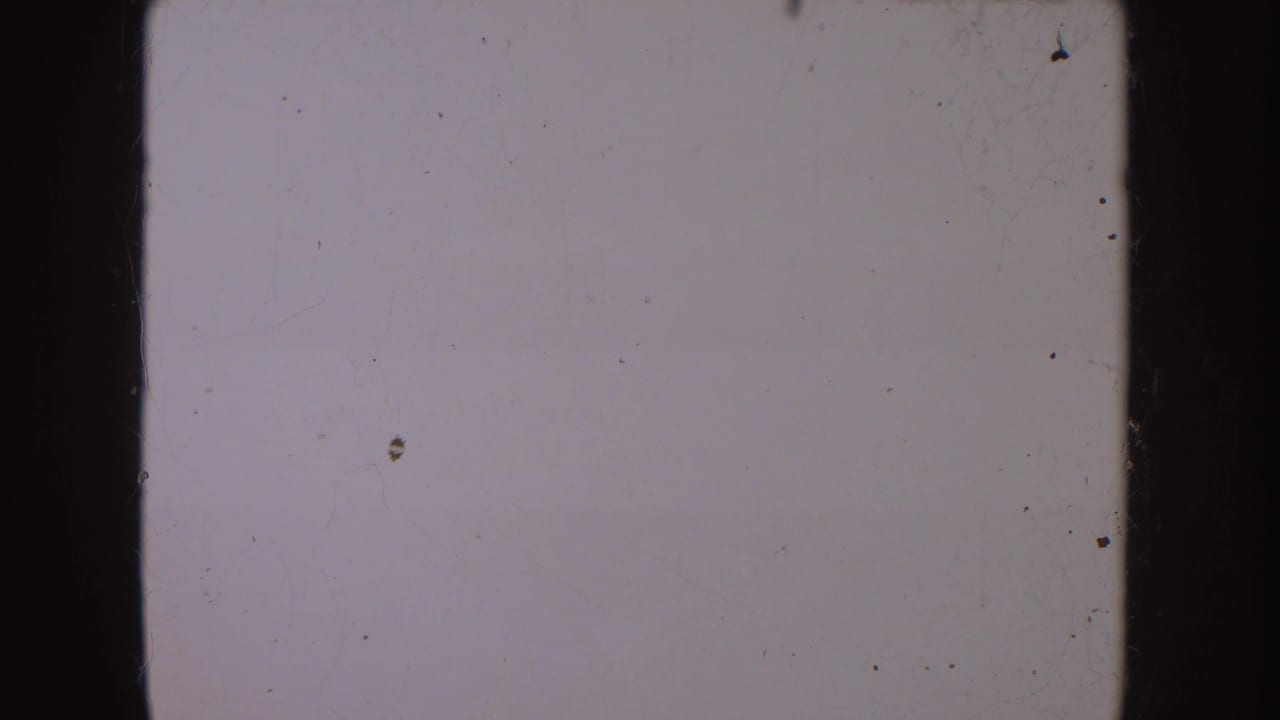 End-of-clip 8mm frame showing a mostly blank, pale film area with scratches, dust, and edge marks.