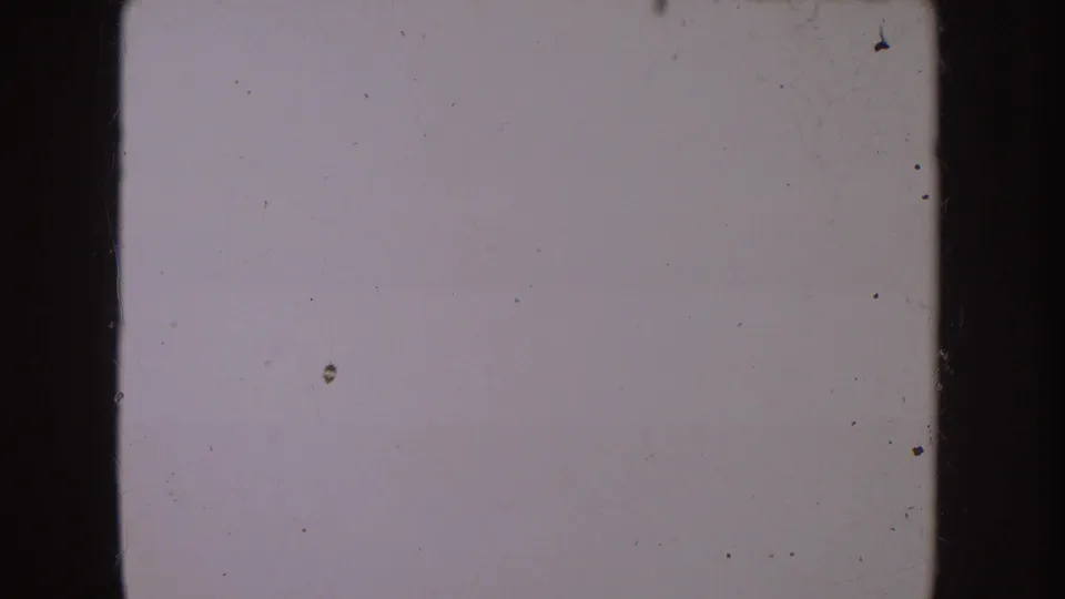 End-of-clip 8mm frame showing a mostly blank, pale film area with scratches, dust, and edge marks.
