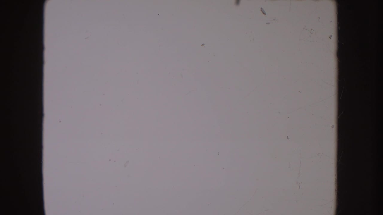 Blank or overexposed 8mm frame from the 1954 South Dakota home-movie clip, showing grain, scratches, and dark frame borders.