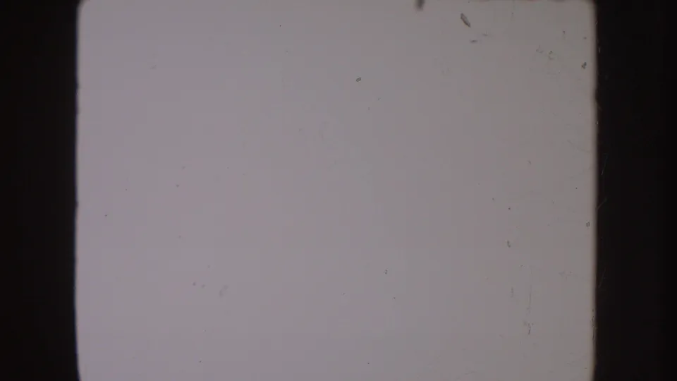 Blank or overexposed 8mm frame from the 1954 South Dakota home-movie clip, showing grain, scratches, and dark frame borders.
