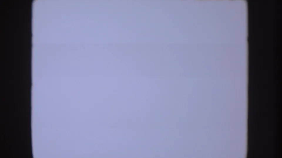 Overexposed 8mm frame with pale blue-white field and dark film edges, likely part of the same 1954 South Dakota home-movie clip.