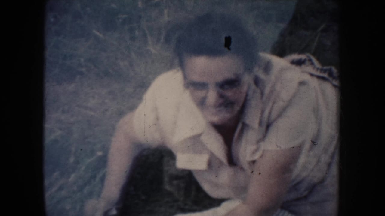 The woman sits up on the grass and smiles toward the camera in this 1954 South Dakota 8mm home-movie frame.