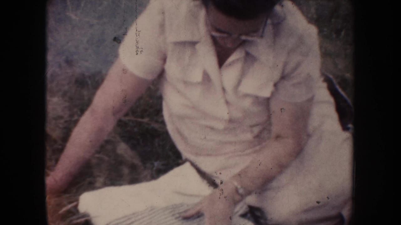 Woman looking down while folding or arranging a checked cloth outdoors.