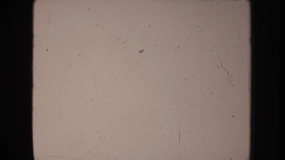 Faded 8mm frame from the clip with heavy exposure loss, dust, scratches, and dark film borders.