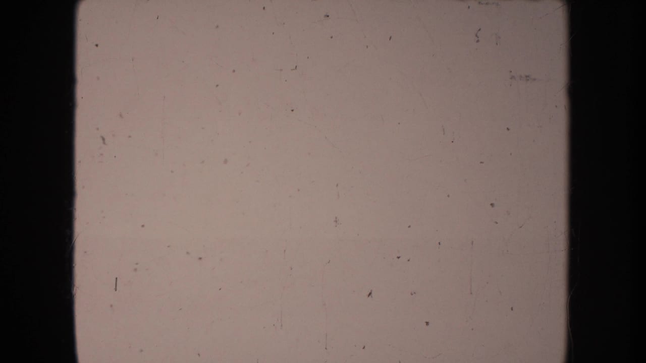 Mostly blank faded 8mm frame with scratches and dark vertical borders.