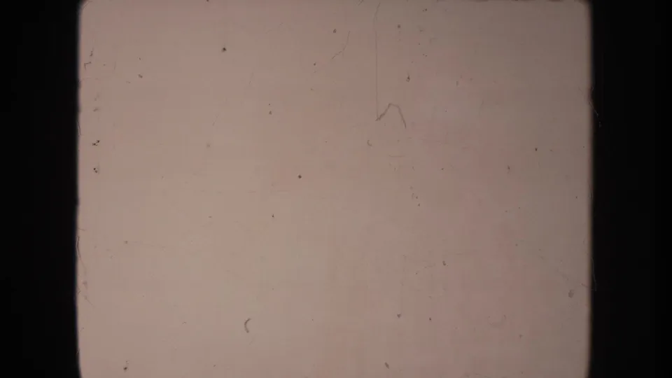 A soft, faded 8mm frame with visible film wear and no clear subject before the couple appears.