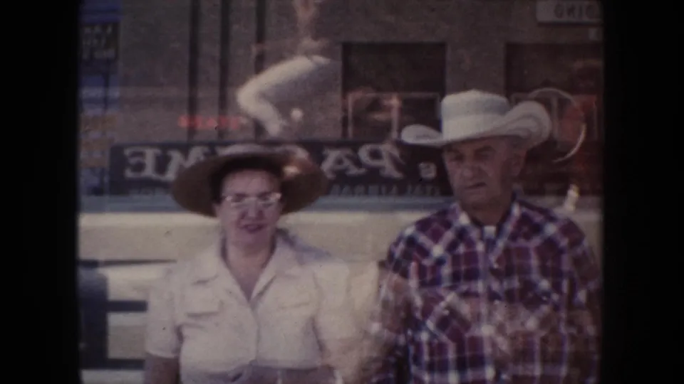 An older woman in glasses and a wide-brimmed hat stands beside a man in a white cowboy hat in 1954 South Dakota footage.