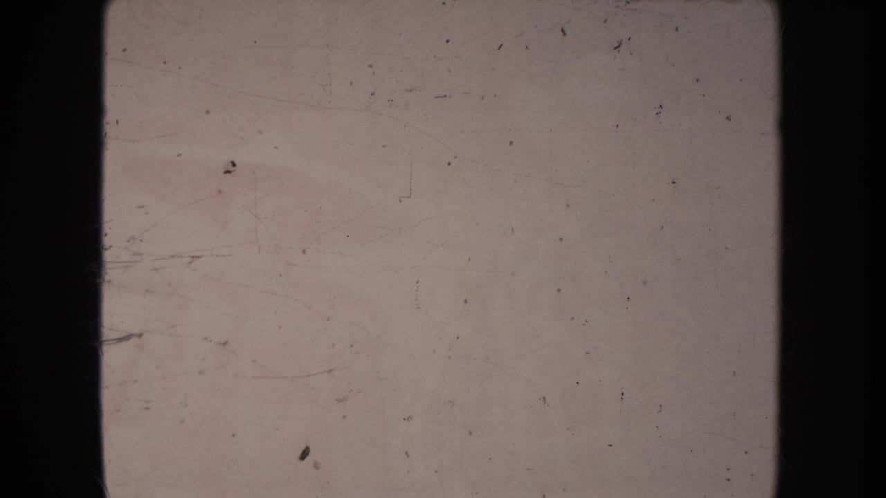 Mostly blank, scratched film frame with dark borders and pale exposure.