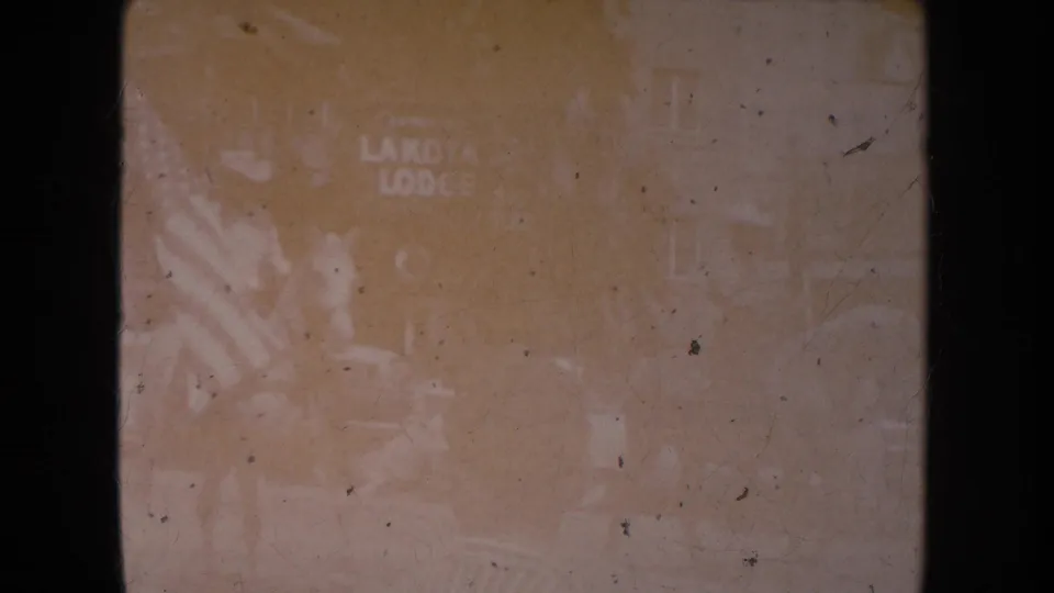 A very faded 1954 South Dakota frame shows partial sign text and indistinct shapes, with details obscured by exposure and film wear.