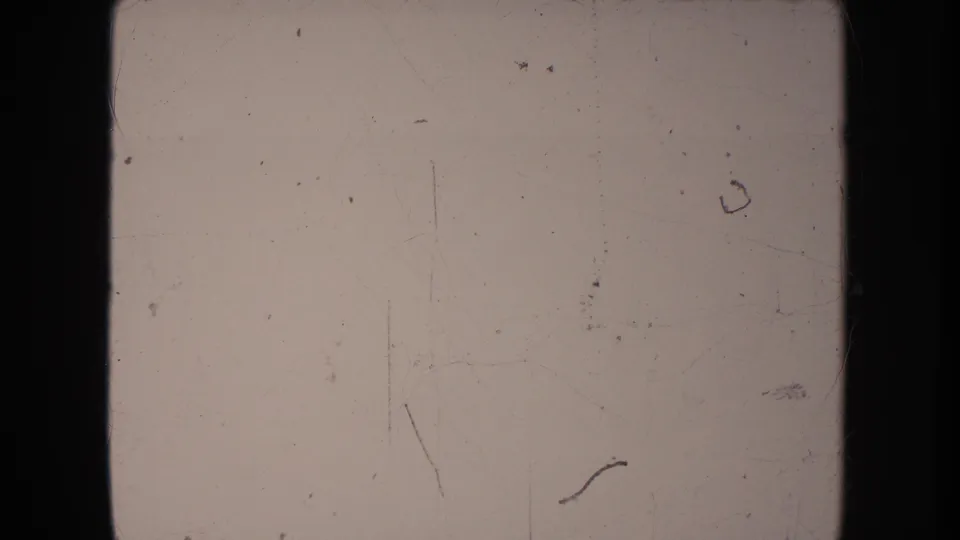 Pale 1950s 8mm home-movie frame from the South Dakota clip, showing film wear and little readable scene detail.