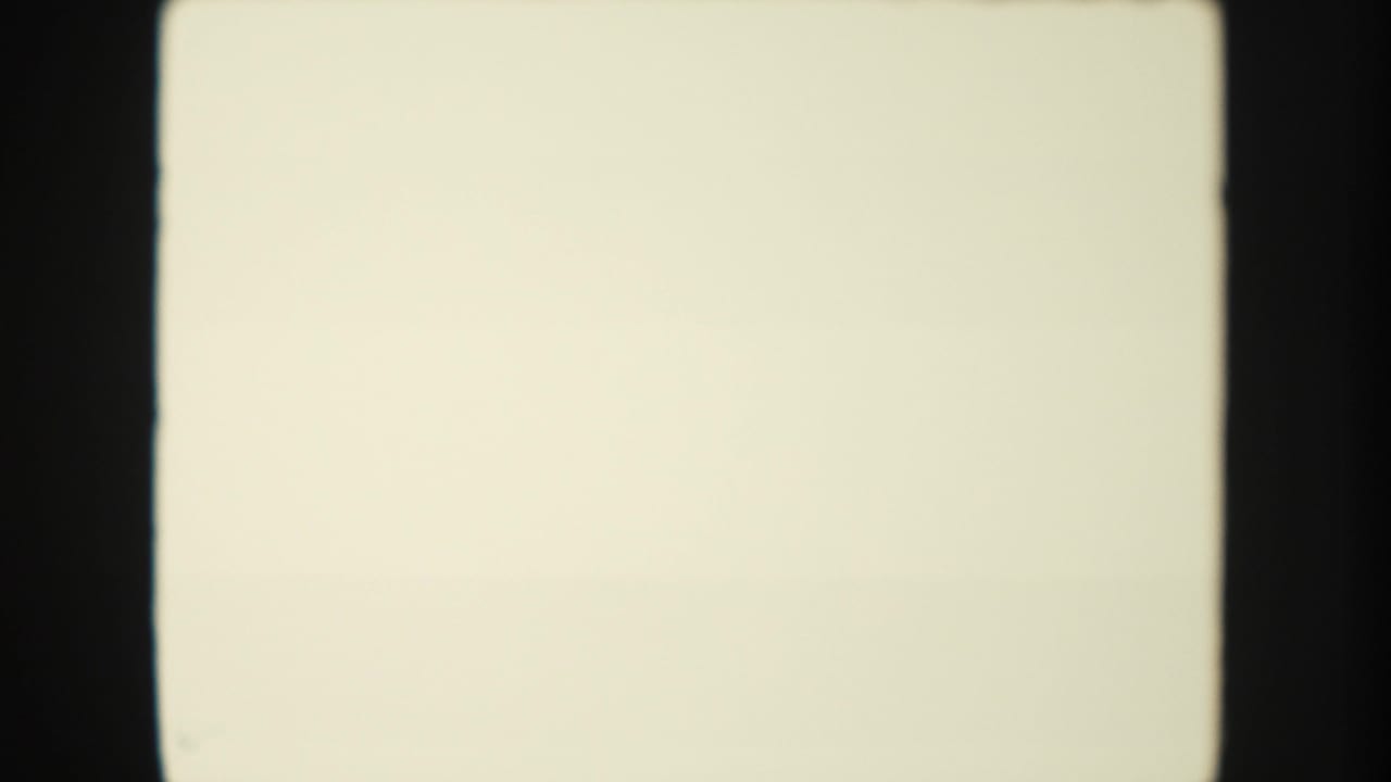 Blank 8mm film leader with pale exposure field, dark gate edges, and no visible scene content.