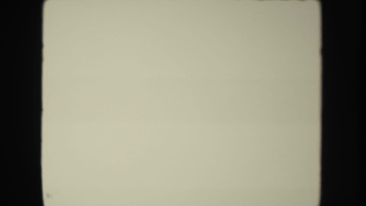 Pale blank leader frame from the 8mm scan, bordered by dark film edges and subtle surface marks.