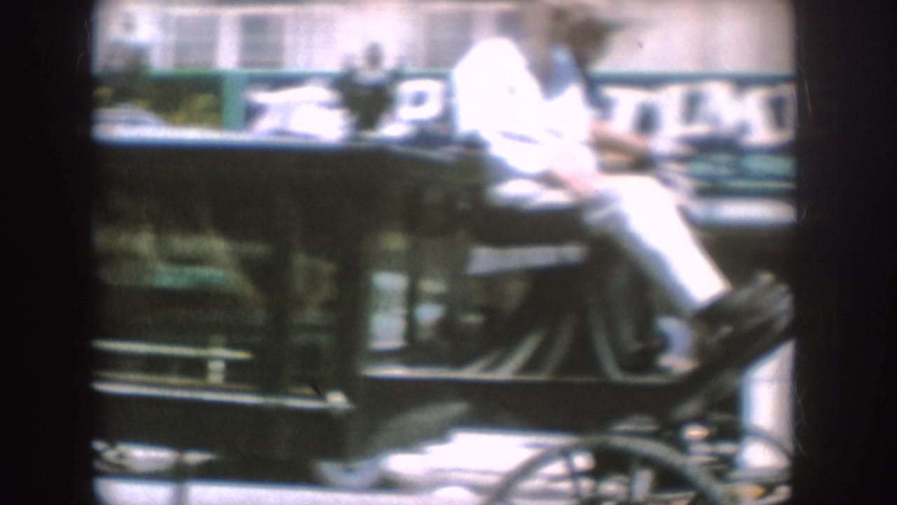 1954 South Dakota frame showing a brightly exposed rider on a horse-drawn carriage moving past main-street storefronts.