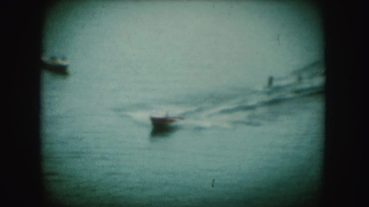 1954 South Dakota 8mm frame showing a small boat moving across open water with a trailing wake.