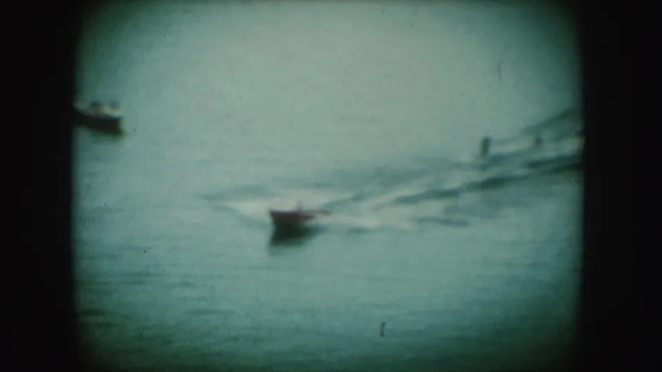 1954 South Dakota 8mm frame showing a small boat moving across open water with a trailing wake.