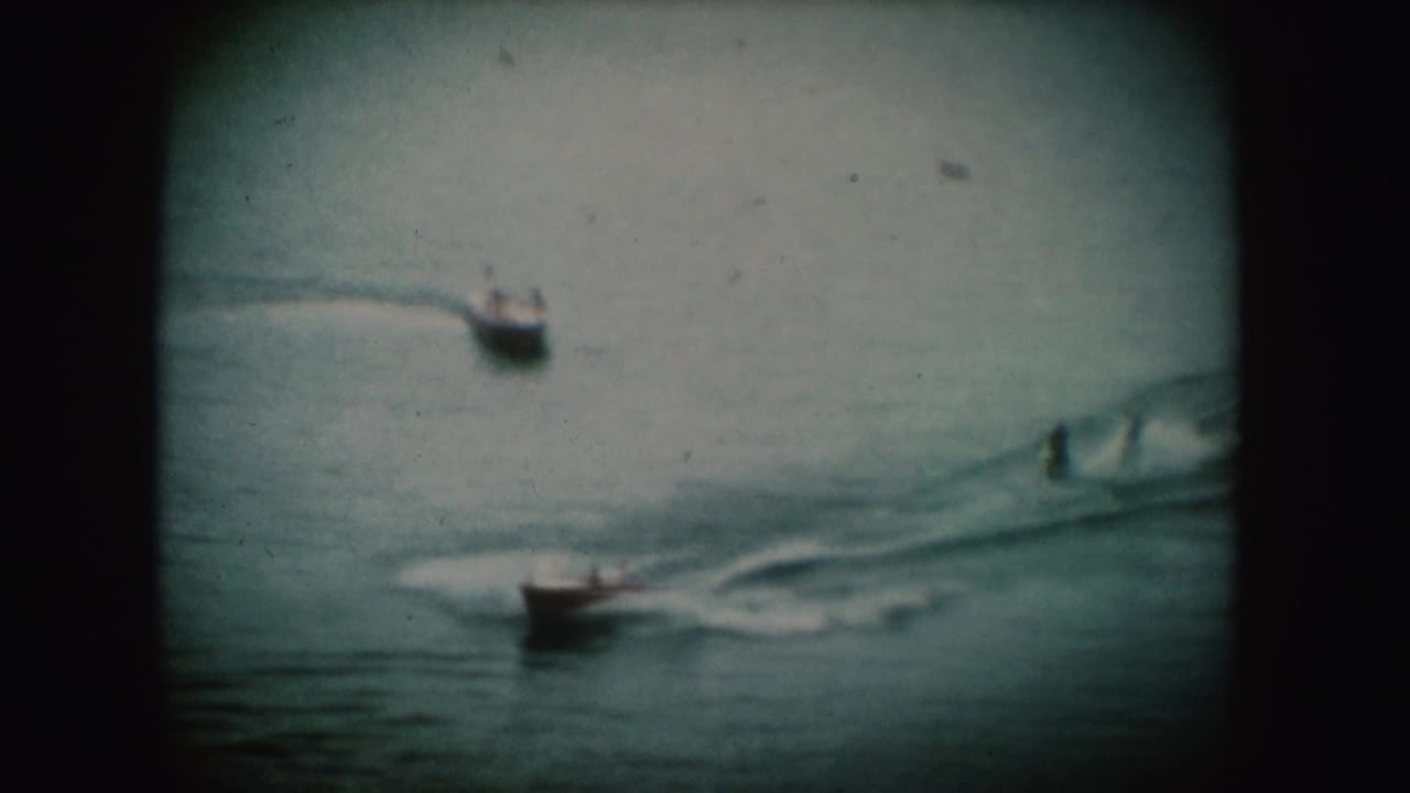 1954 South Dakota home-movie frame showing small boats moving across water, with wakes visible on the surface.