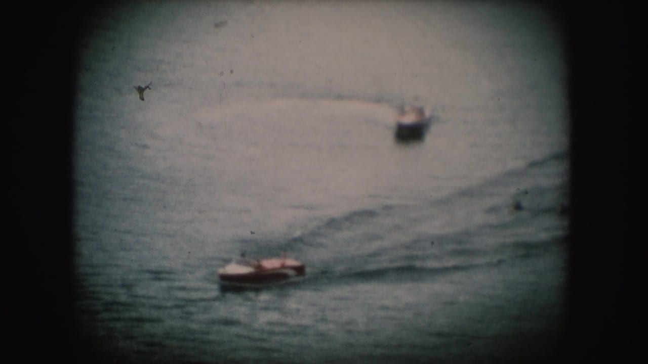 1954 South Dakota 8mm frame showing a small motorboat on rippled water, with another boat blurred in the background.