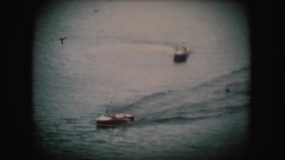 1954 South Dakota 8mm frame showing a small motorboat on rippled water, with another boat blurred in the background.