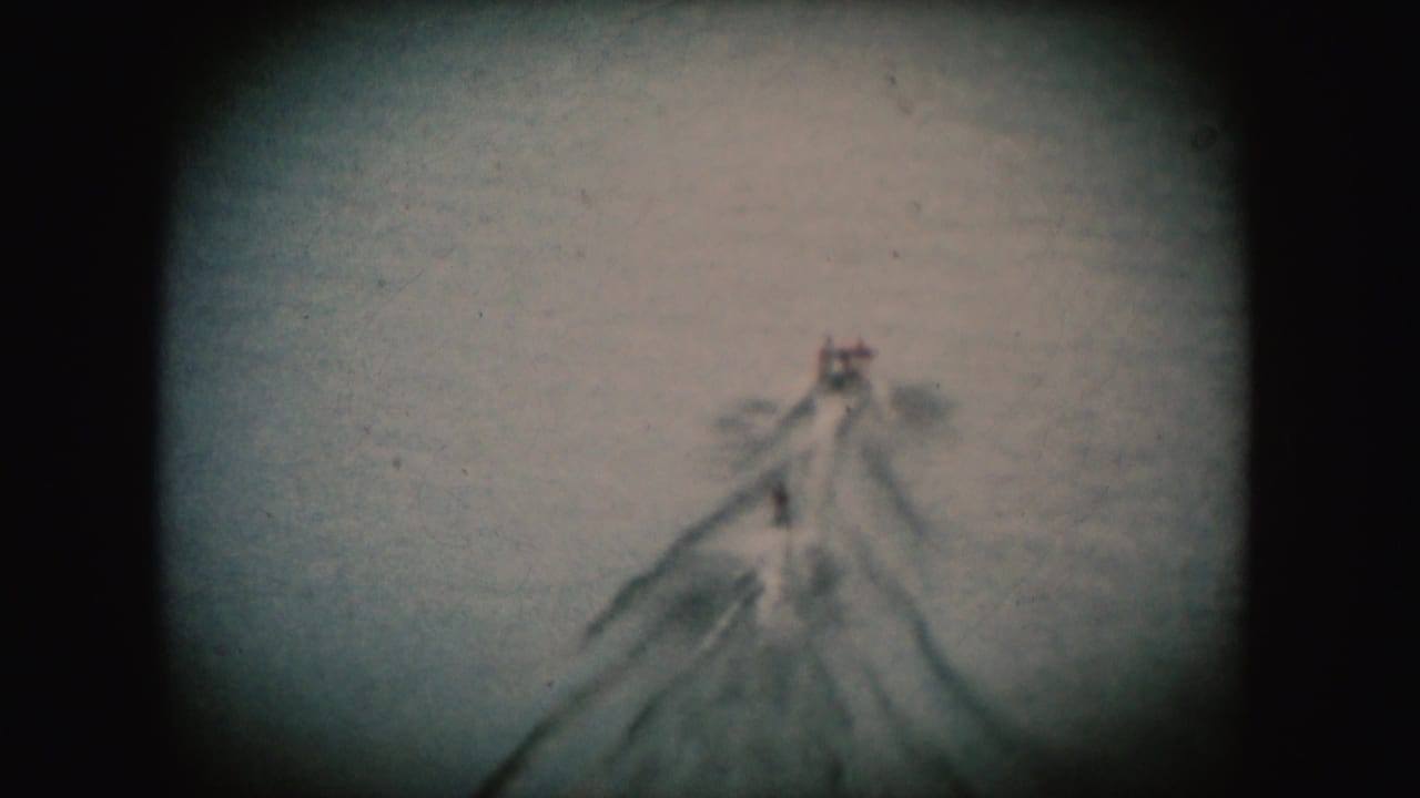 Soft 8mm view of a boat towing a water skier on a South Dakota river, with the subject small and blurred.