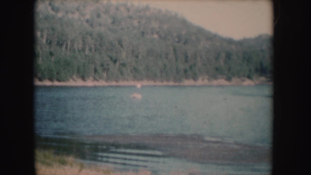 Forested hillside and lake shoreline seen through rounded 8mm frame edges.