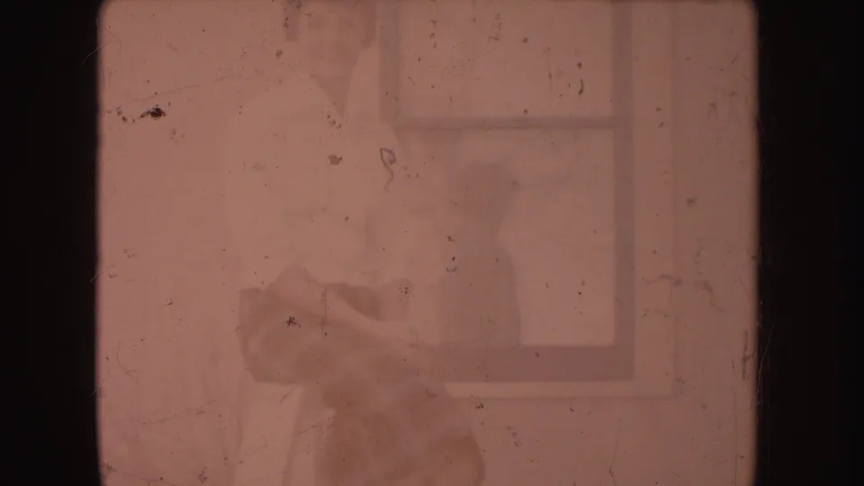 Faded 8mm end frame with pink discoloration, dust marks, scratches, and indistinct shapes near a window-like edge.