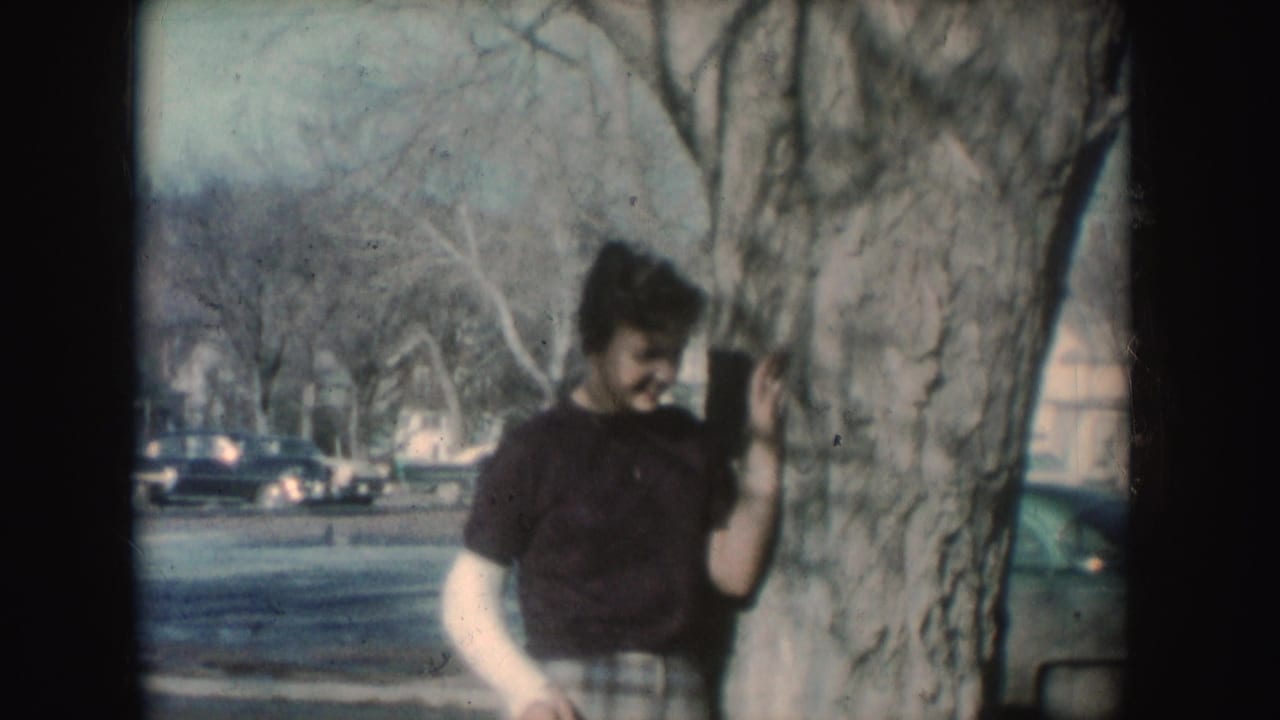 Young woman with a cast leans against a tree and looks downward.