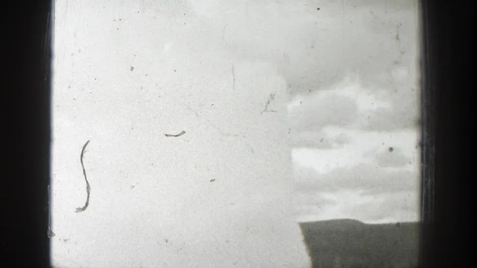 1939 Wyoming 8mm frame showing a pale geyser plume and cloudy sky partly blocked by dark window framing.