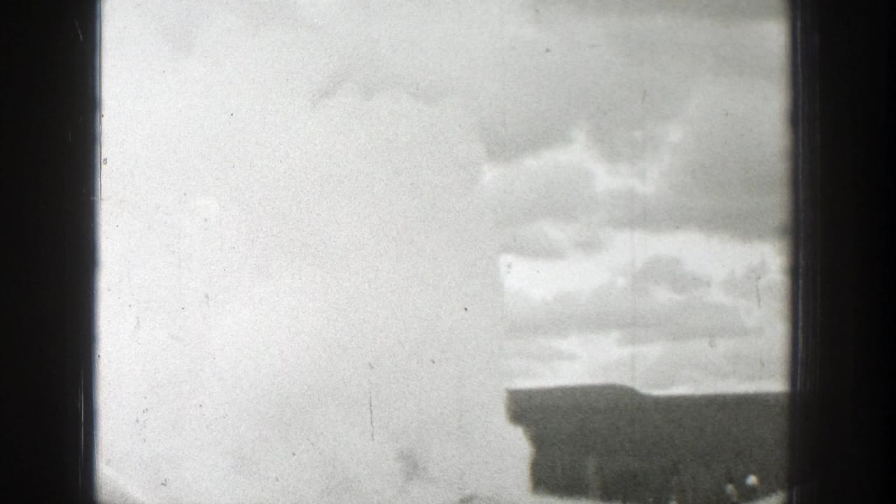 Cloudy sky above a dark roofline seen through 8mm frame edges.