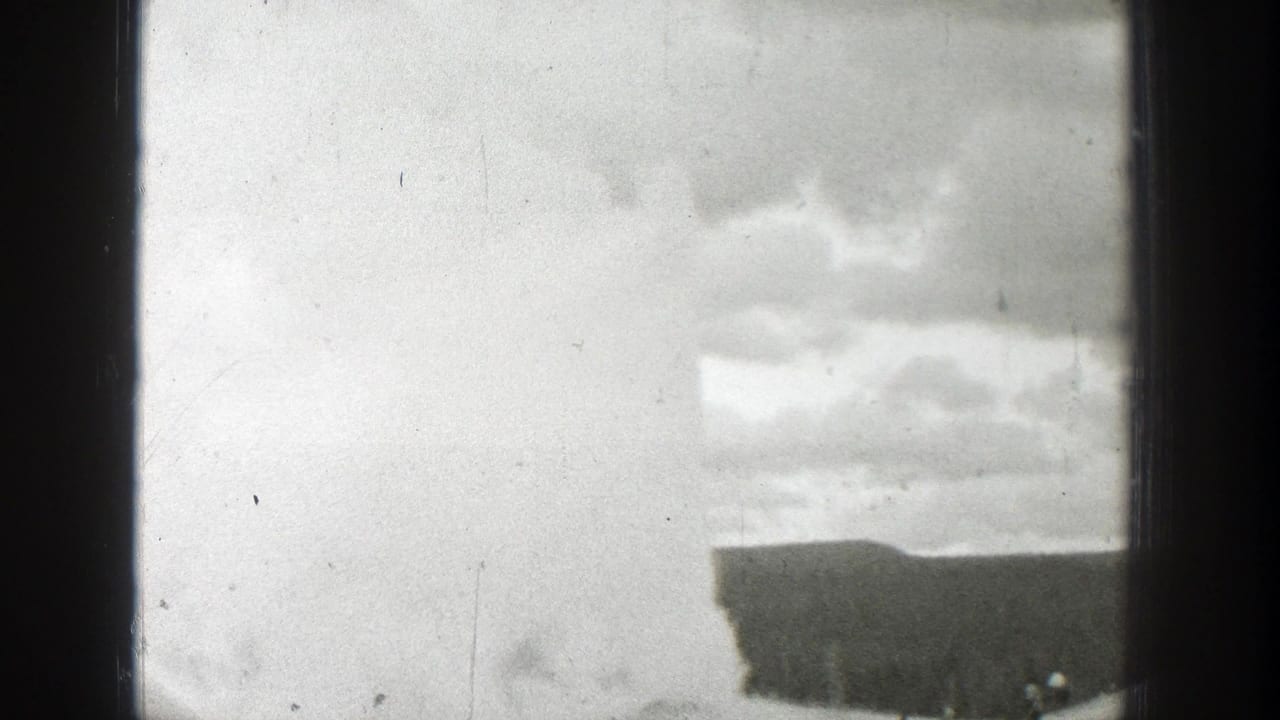 Cloudy sky and a dark building edge framed by 8mm film borders.