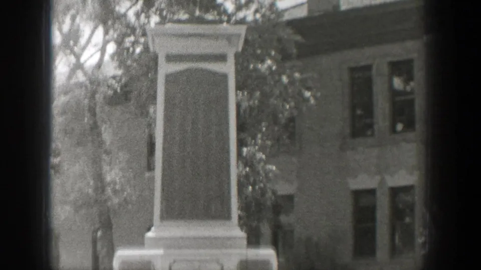 1939 Wyoming 8mm frame with the monument centered, showing its upper plaque area, trees, and background building windows.