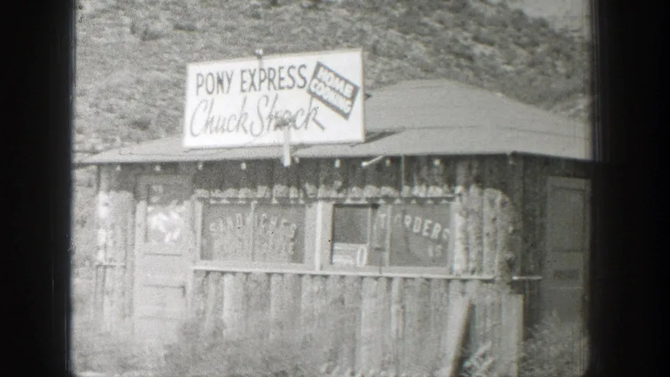 1939 Wyoming 8mm frame showing a rustic roadside food stand with Pony Express Chuck Shock signage against an arid hillside.