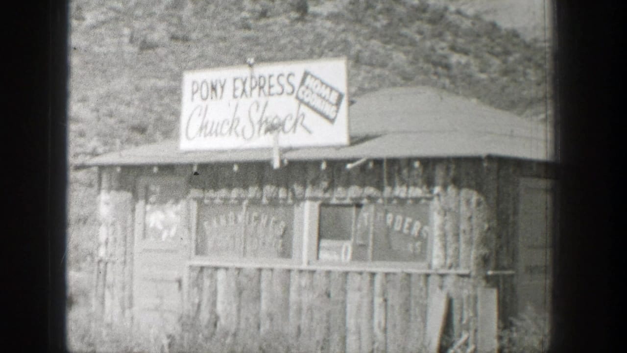 Rustic wooden roadside building with large food-service signs above the roof.