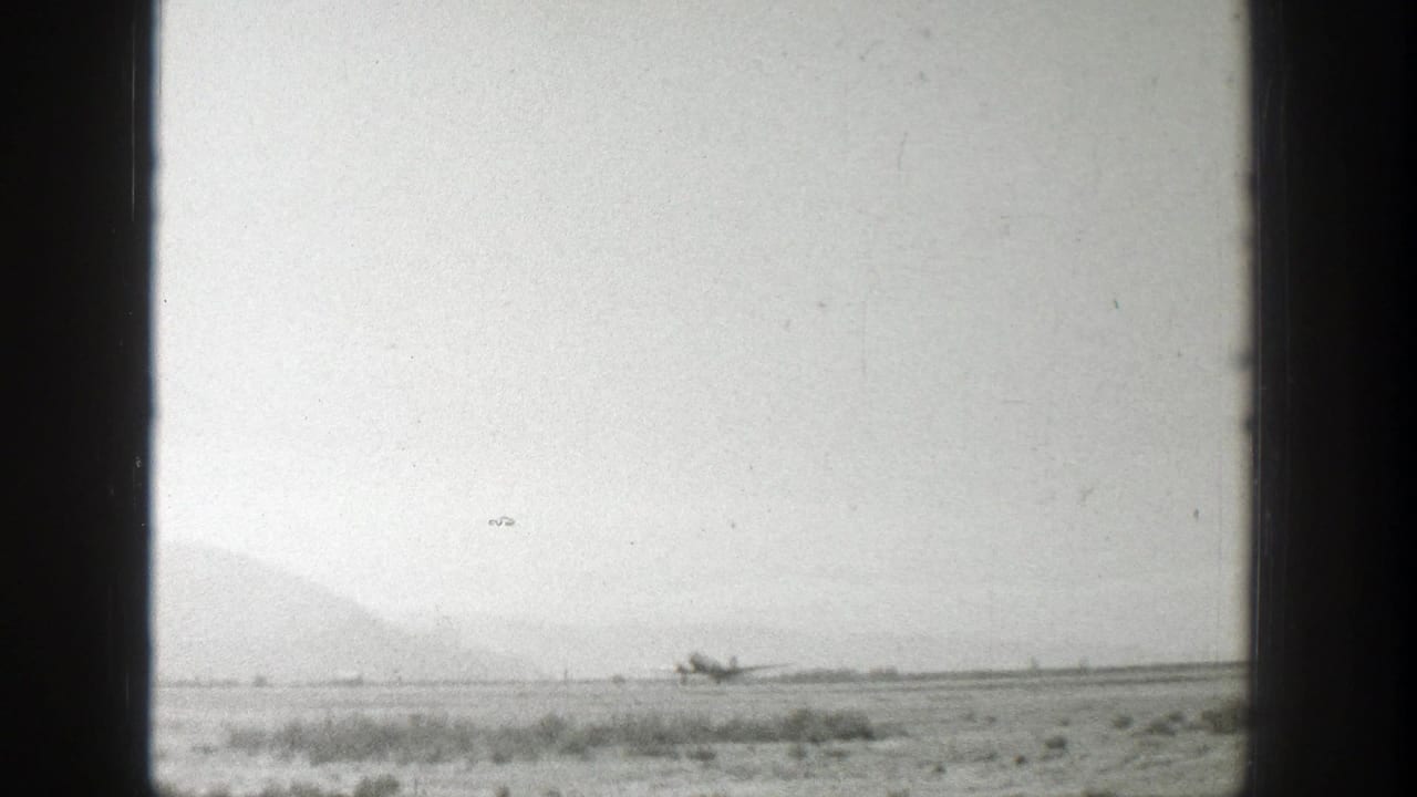 Small airplane on an open field, partly framed by dark vertical edges.