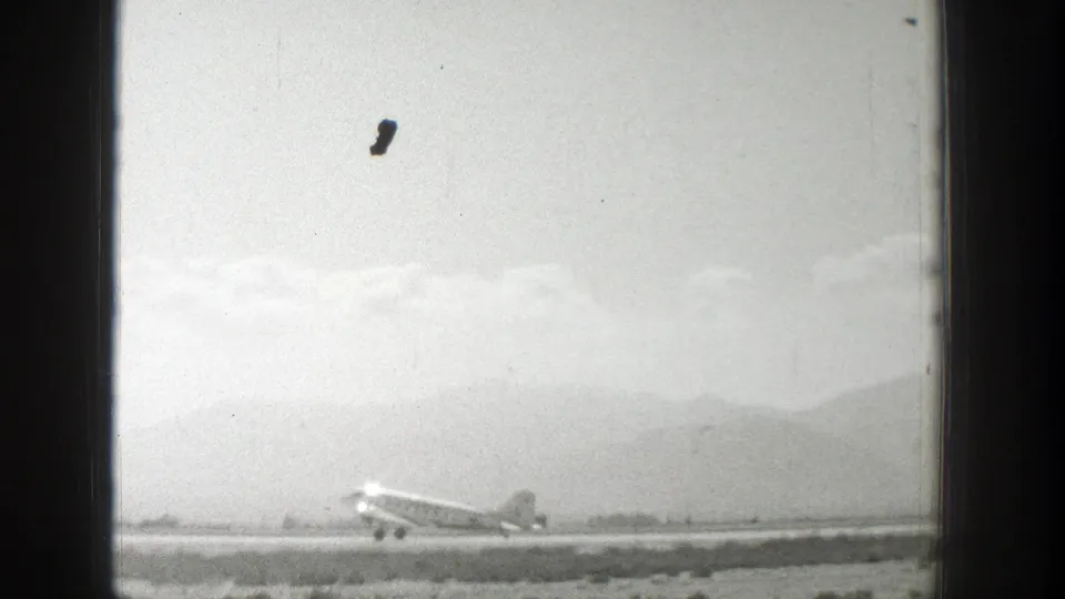 1939 Wyoming frame of a propeller airplane on or just above the runway, seen through faded 8mm film texture.
