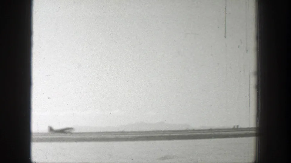 Distant propeller aircraft on a Wyoming runway in a soft black and white 8mm frame from 1939.