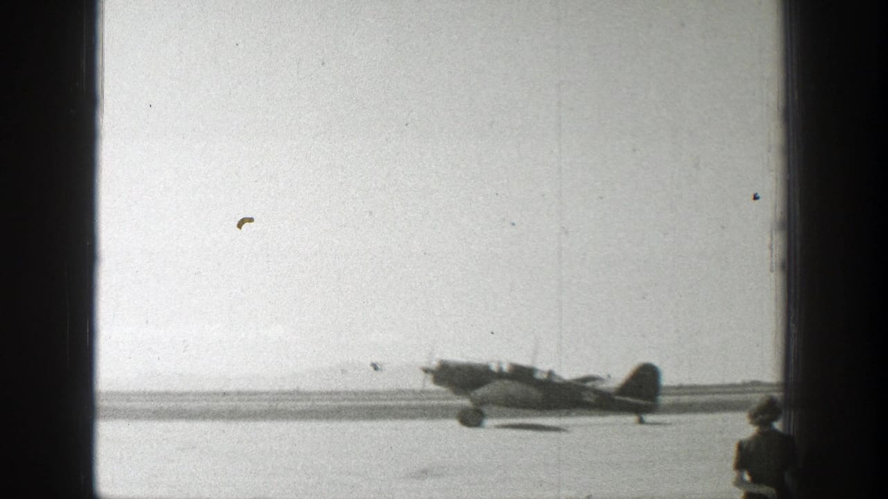 1939 Wyoming home-movie frame showing a small propeller plane on an airfield with runway and open sky behind it.