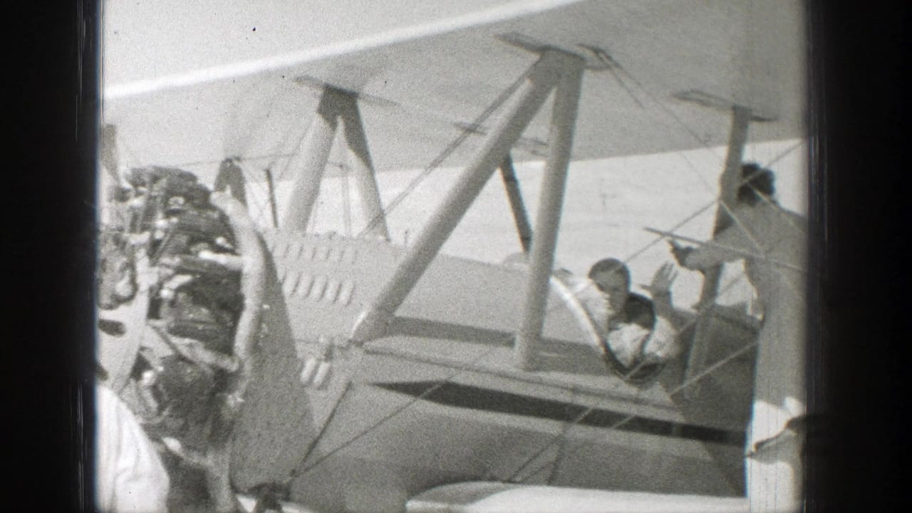 Biplane side view with radial engine, open cockpit, and people near the fuselage.