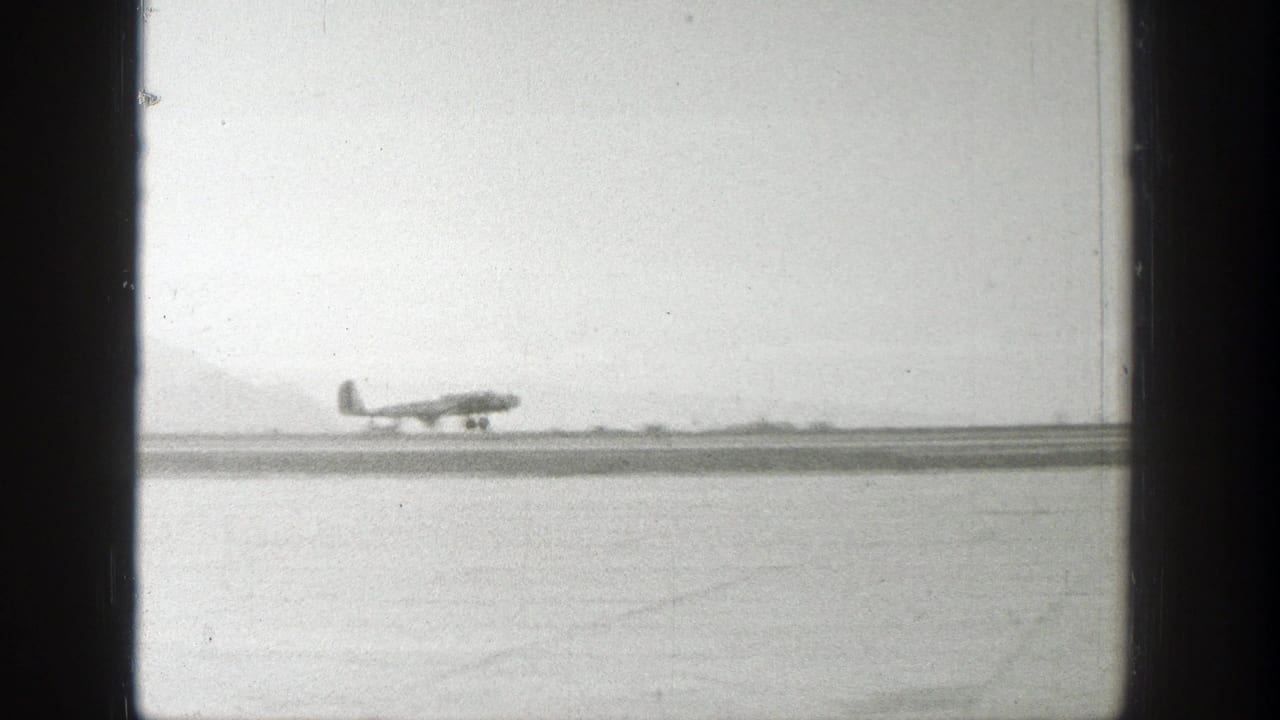 A small airplane appears on a Wyoming airfield runway with a hazy mountain backdrop in 1939 home-movie footage.