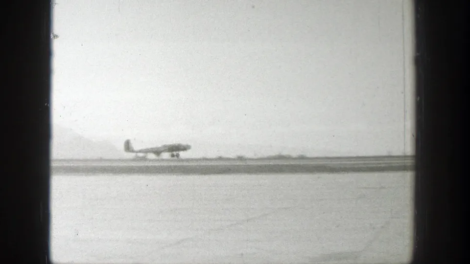 A small airplane appears on a Wyoming airfield runway with a hazy mountain backdrop in 1939 home-movie footage.